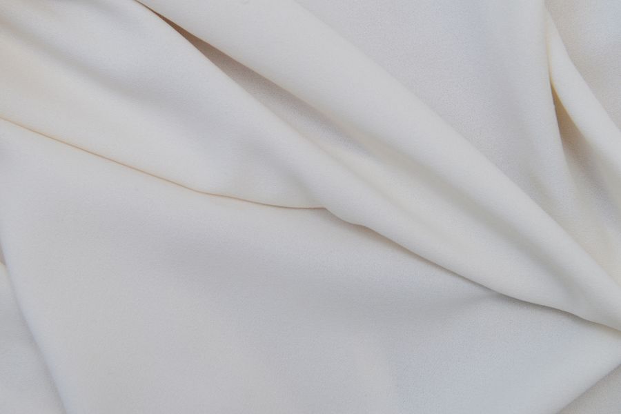 Close-up of elegant white fabric with smooth folds and texture details.