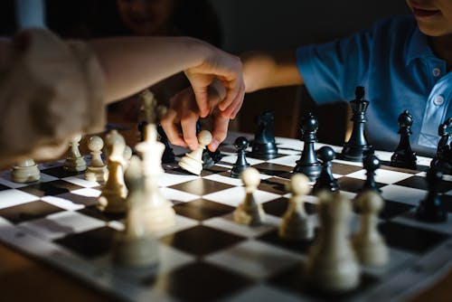 Photo of Hands Moving Chess Pieces