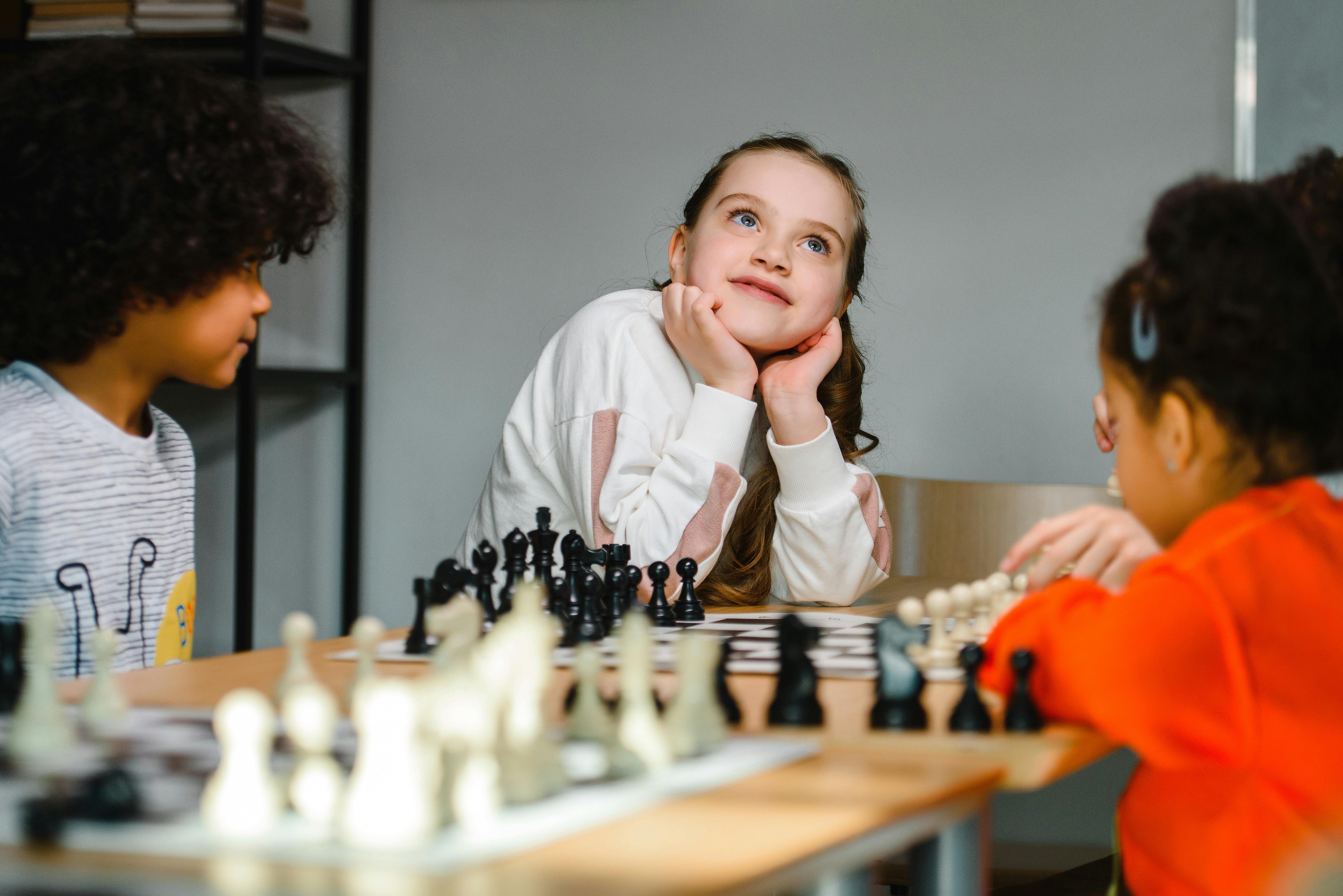 Kids playing chess indoors, focusing on strategy and creativity, showcasing diversity and playful learning.