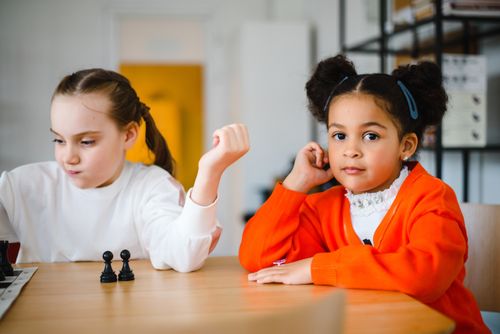 Free Two young girls engaged in a playful chess game indoors, showcasing focus and friendship. Stock Photo