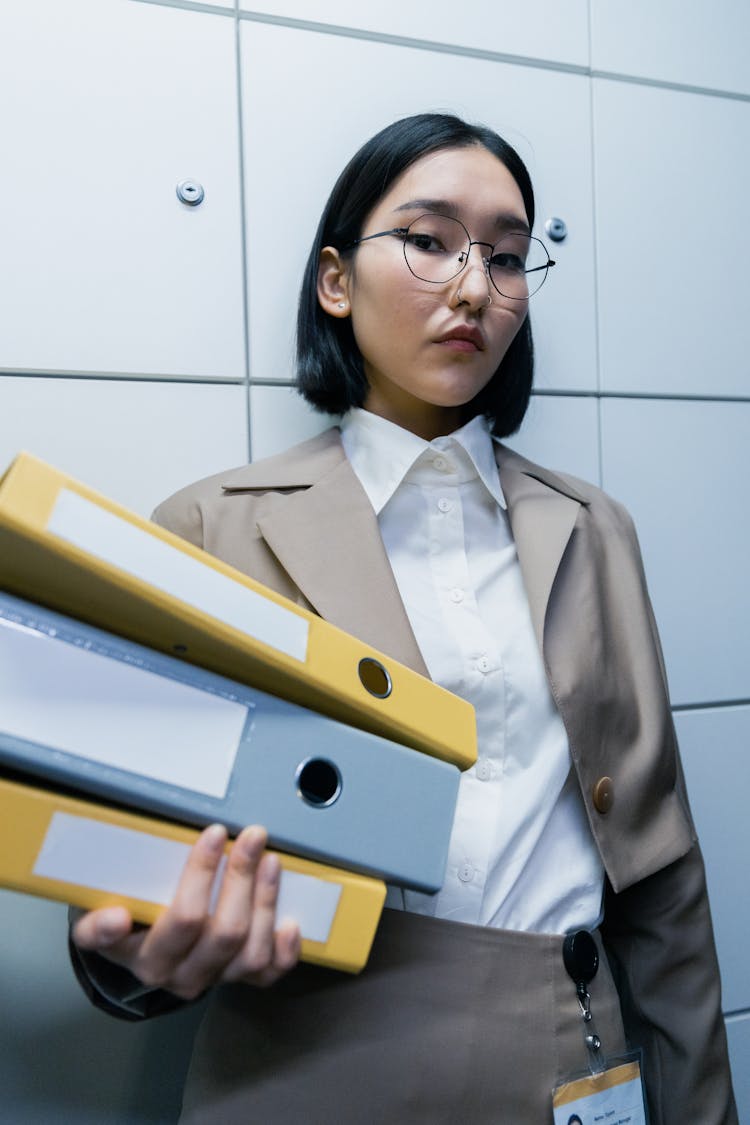 Woman In Brown Blazer Holding Files In Binders