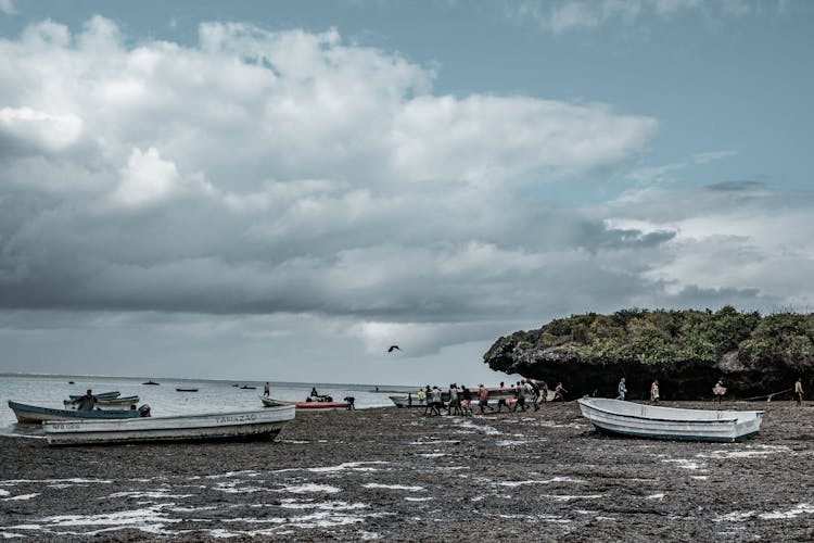 Group Of People Carrying A Wooden Boat Together