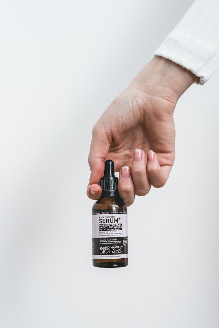 Person Holding Brand Logo Serum Bottle