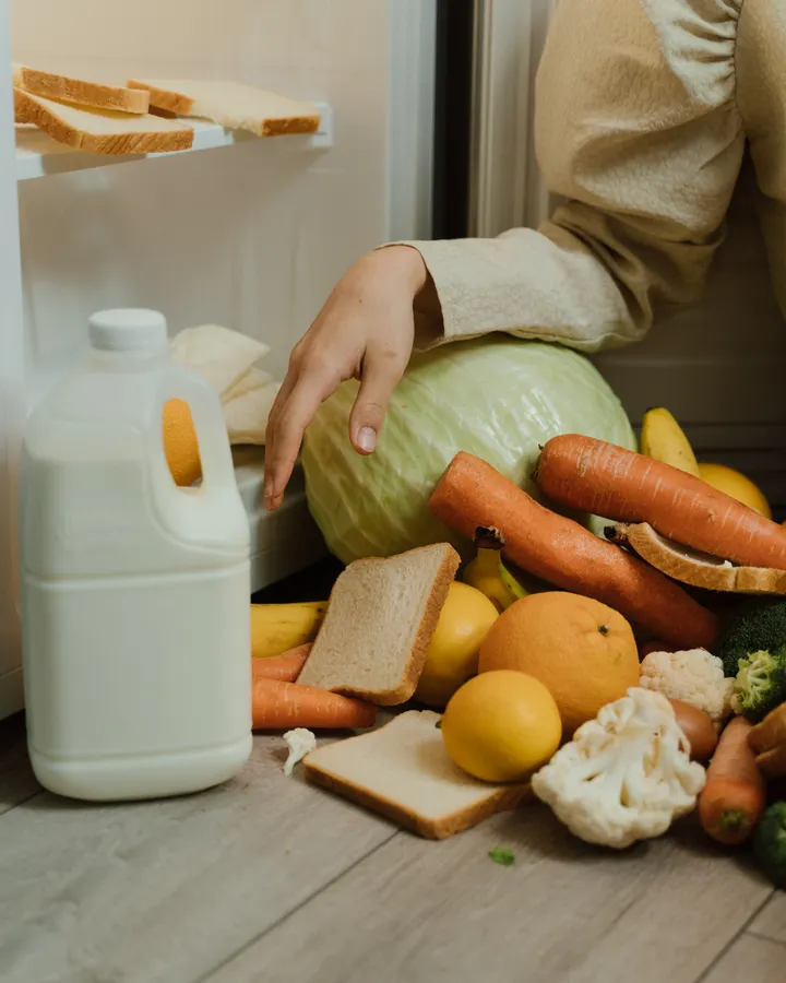 Amana refrigerator repair in La Mesa, CA Person picking up vegetables and bread from the floor of an open refrigerator, Amana refrigerator repair in La Mesa