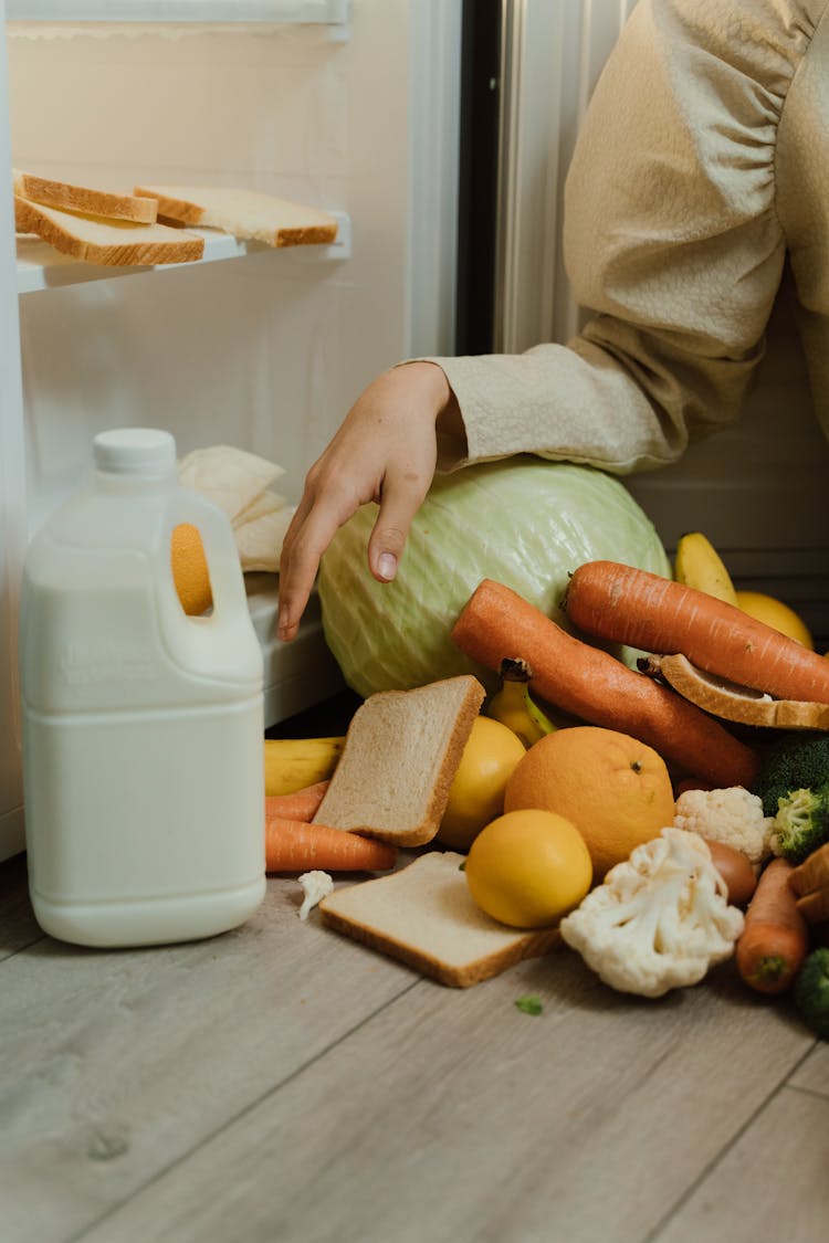 Person Removing Food On The Refrigerator 