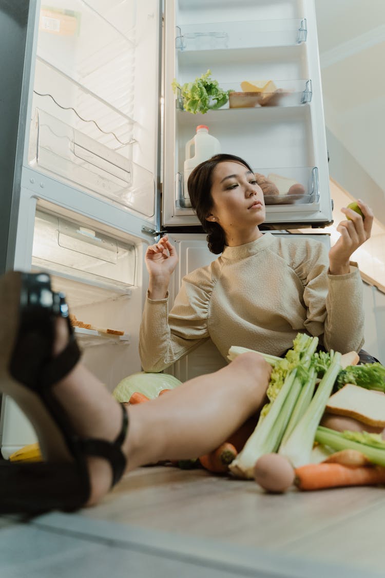 Woman Sitting Beside A Refrigerator