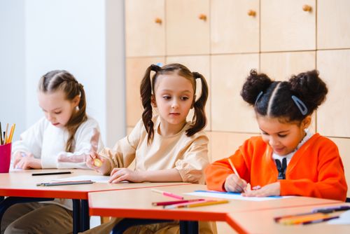 Free Three young girls working enthusiastically on classwork at school, highlighting active learning. Stock Photo