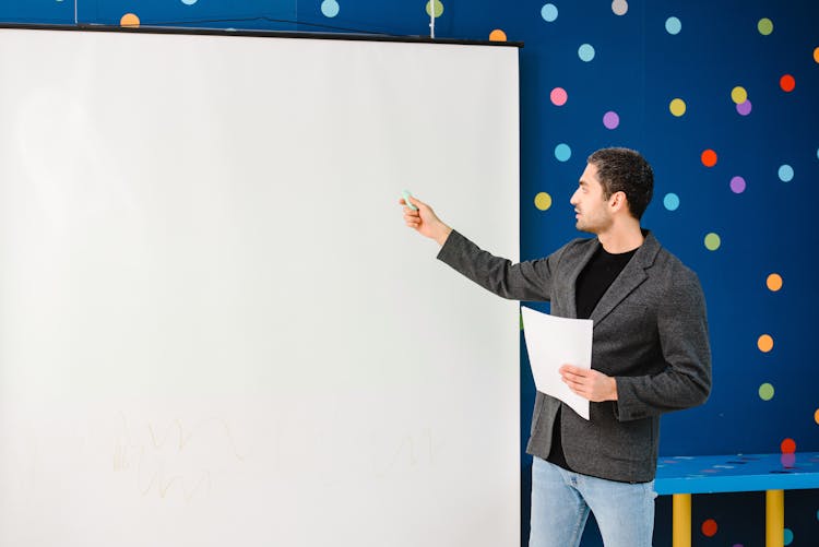 Teacher Pointing At A Projector Screen