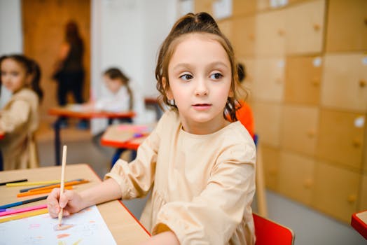 A young girl sitting at a desk coloring with crayons in an elementary school classroom.