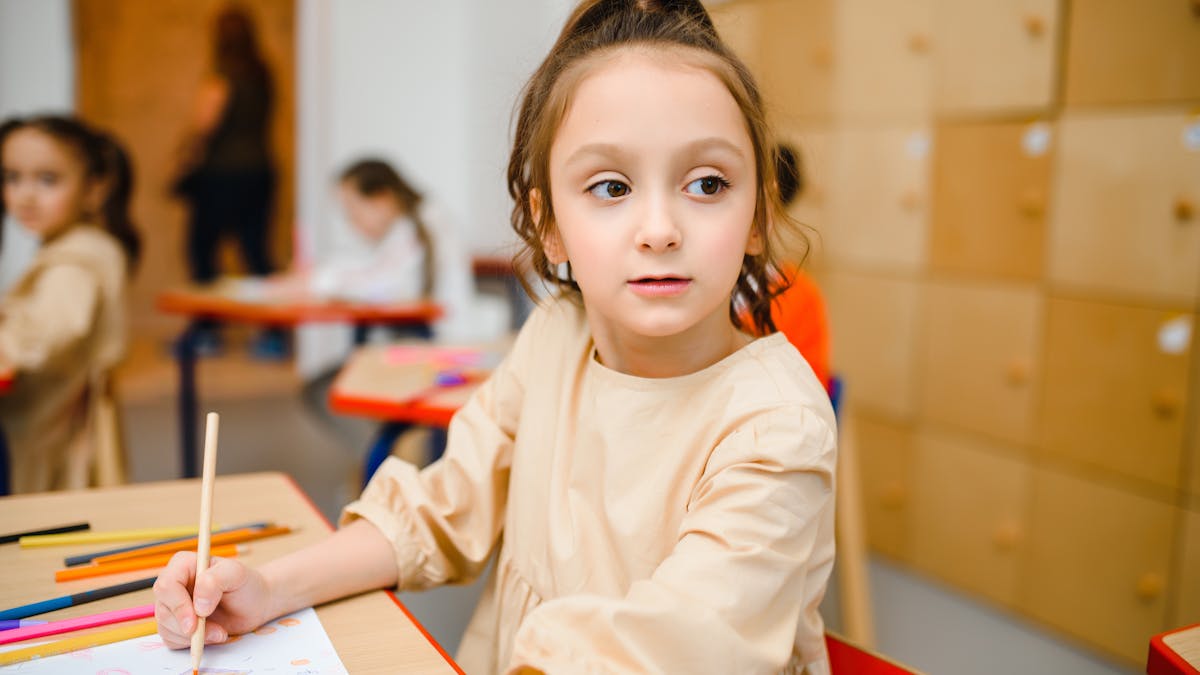 Anak TK sedang mewarnai worksheet di meja