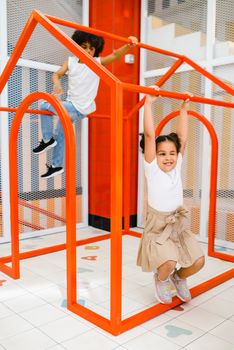 Kids having fun on a vibrant red playground indoors, showcasing playful energy and joy.