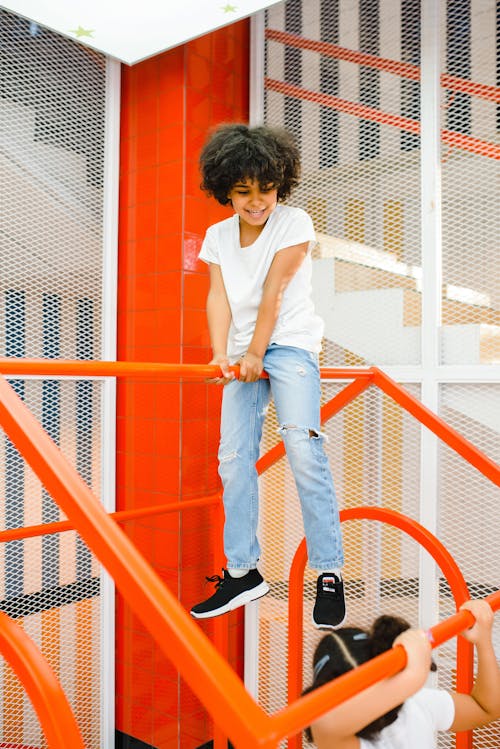 A Young Boy in White Shirt Playing on Metal Railings