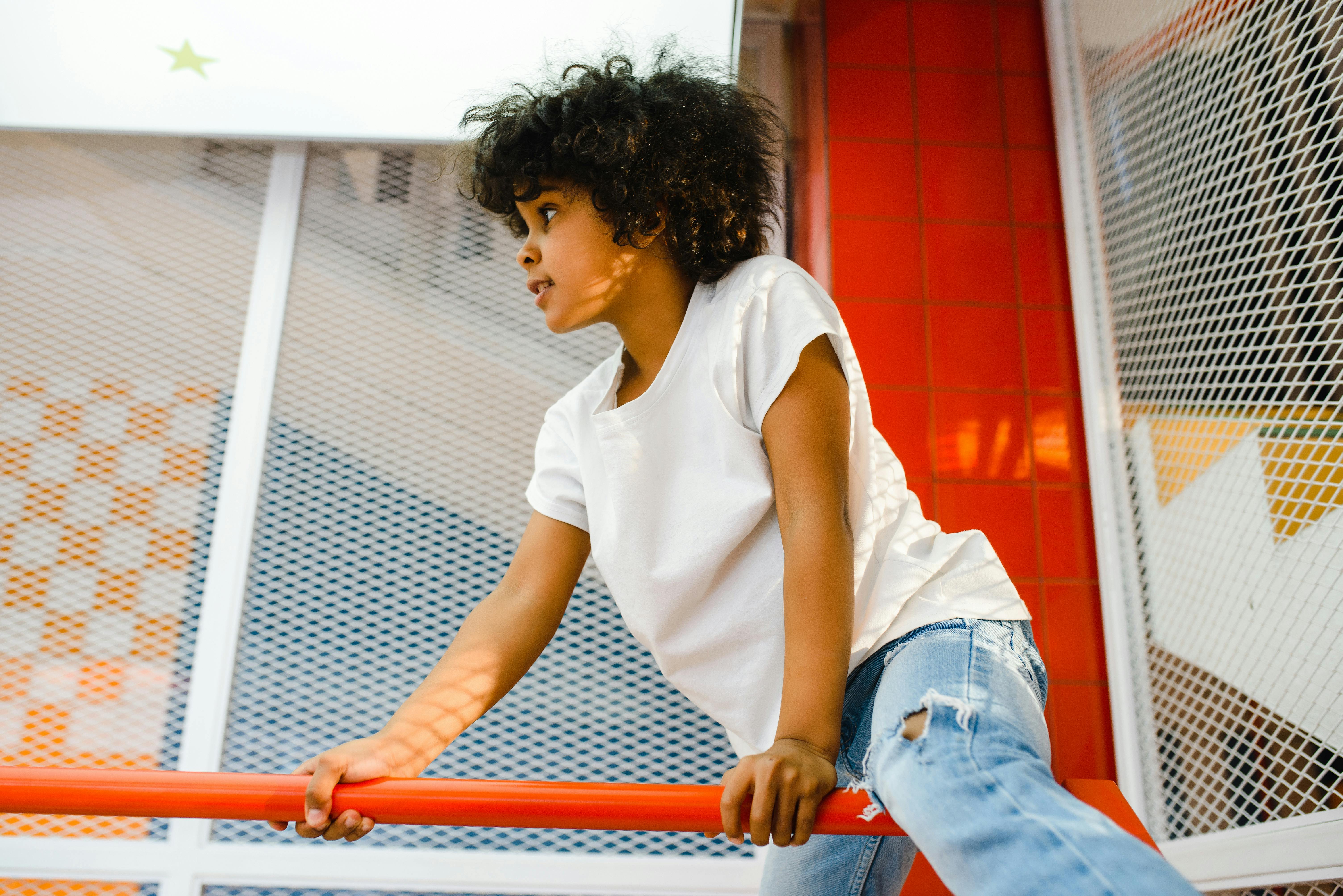 woman in white crew neck t shirt and blue denim jeans sitting on red metal railings