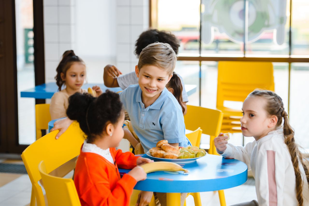 Children eating lunch together in a bright school canteen