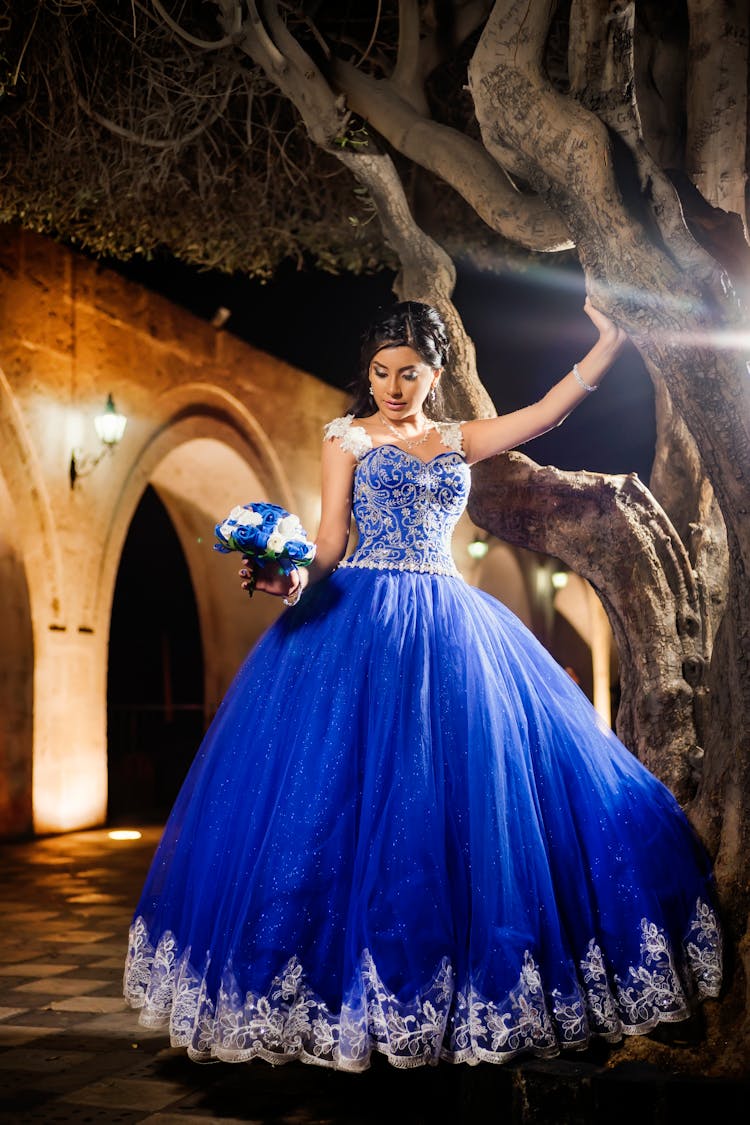 Woman In Blue Quince Dress With A Bouquet Of Flowers