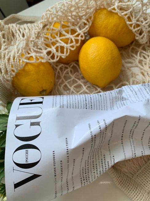 A Vogue magazine beside lemons in a reusable bag, symbolizing sustainable living.