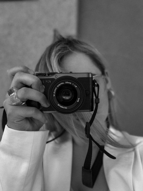 Black and white image of a woman using a camera, capturing an artistic moment.
