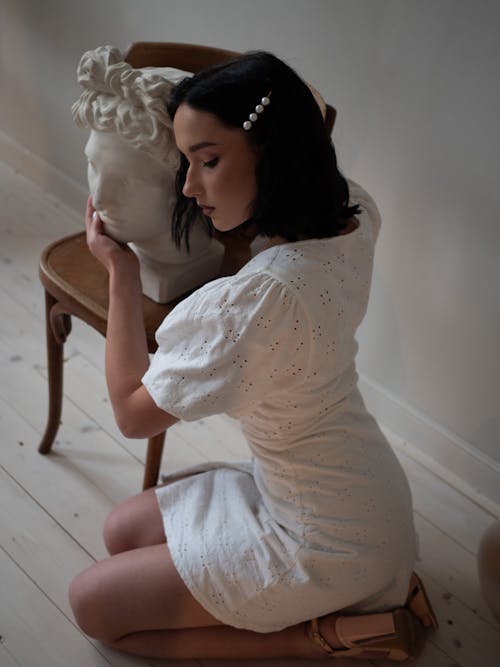 Woman in White Dress hugging a Sculpture