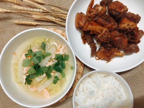 A delicious Vietnamese meal featuring shrimp soup, braised pork, and white rice served on elegant dinnerware.