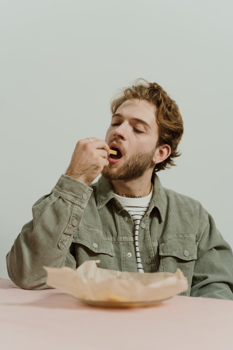 Man Wearing A Jacket Eating French Fries