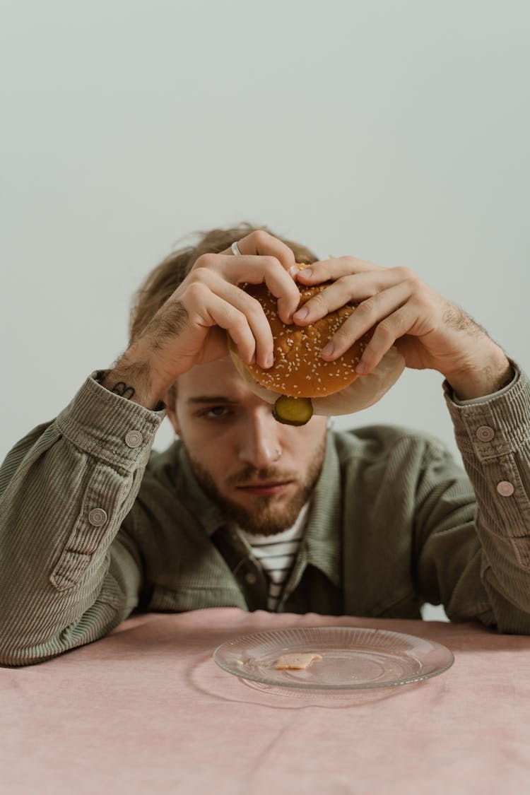 A Man In Gray Jacket Holding Burger