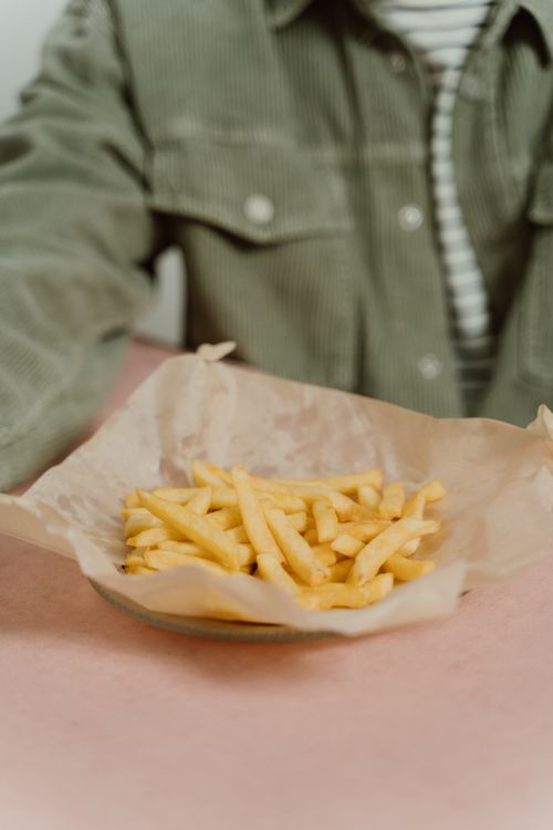 Free Close-up of crispy golden french fries on parchment paper. Stock Photo