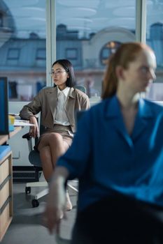 Two women in a contemporary office engaging in work-related activities.