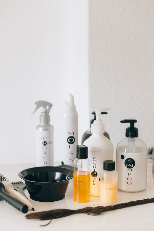 Free A collection of haircare bottles on a white counter with styling tools. Stock Photo