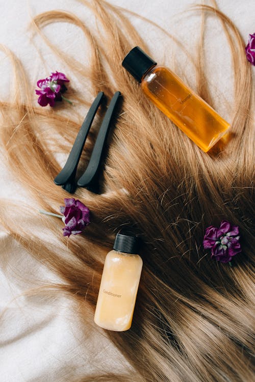 A customer sits in a hair salon chair while a stylist blow-dries their hair. The stylist uses a hairdryer and a brush to create a sleek and voluminous hairstyle. 