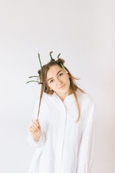 A woman creatively wears asparagus as hair accessories, standing against a white background.