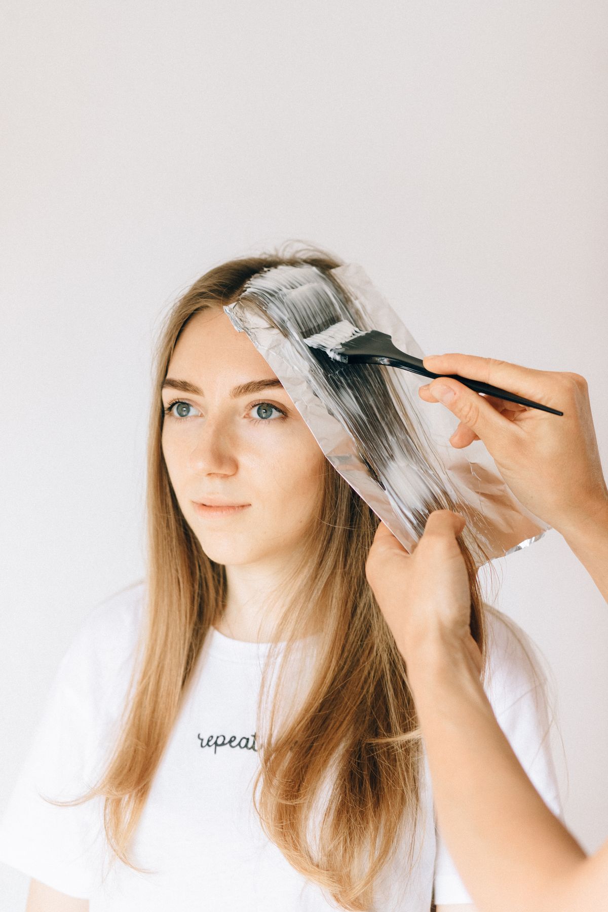 Colourist applying professional toner to blonde hair in a salon