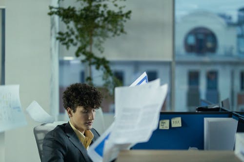 Curly Brunette Man Tossing Documents in an Office