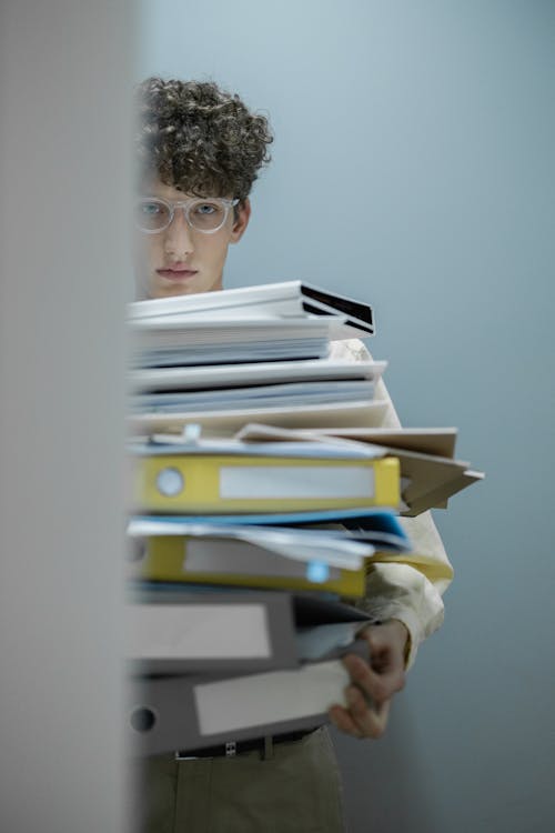 A Man in Yellow Dress Shirt Holding a Pile of Folders
