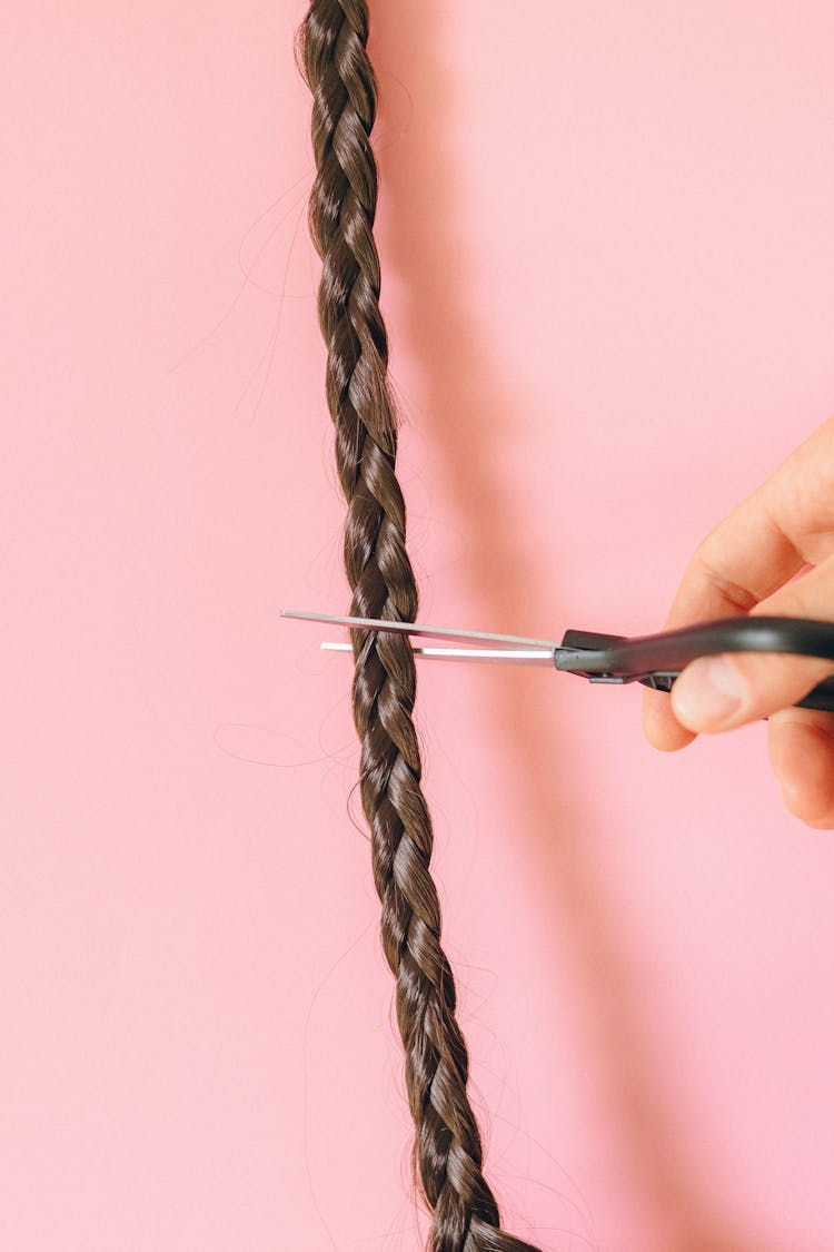 Person Cutting A Braided Hair With Scissors