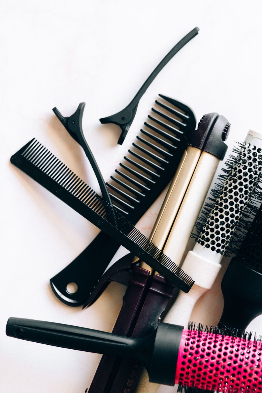 Ciseaux, peignes et outils de coiffure posés sur un comptoir, lumière douce et naturelle.