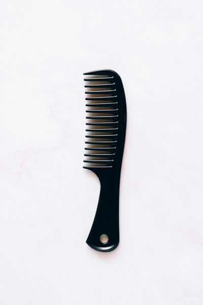Fine-tooth dressing comb laid flat on a pale surface — photo by Nataliya Vaitkevich on Pexels