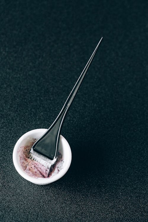 Free Hair Dye Brush and Mixing Bowl on a Black Surface Stock Photo