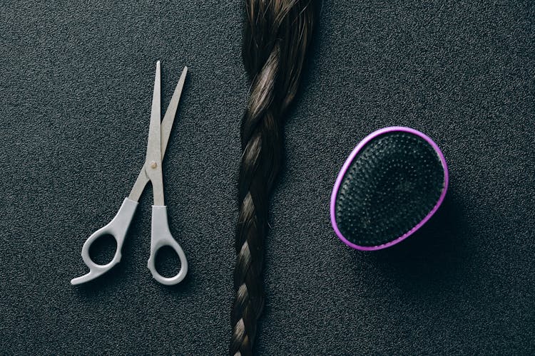 Silver Scissors Beside Black And Purple Hair Brush