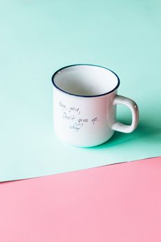 White mug with motivational text on colorful background, encouraging positivity.