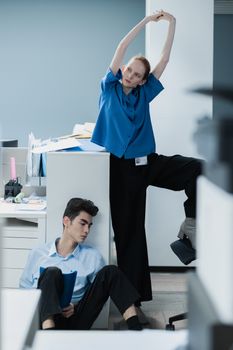 Two office workers take a stretch break to improve focus and productivity.