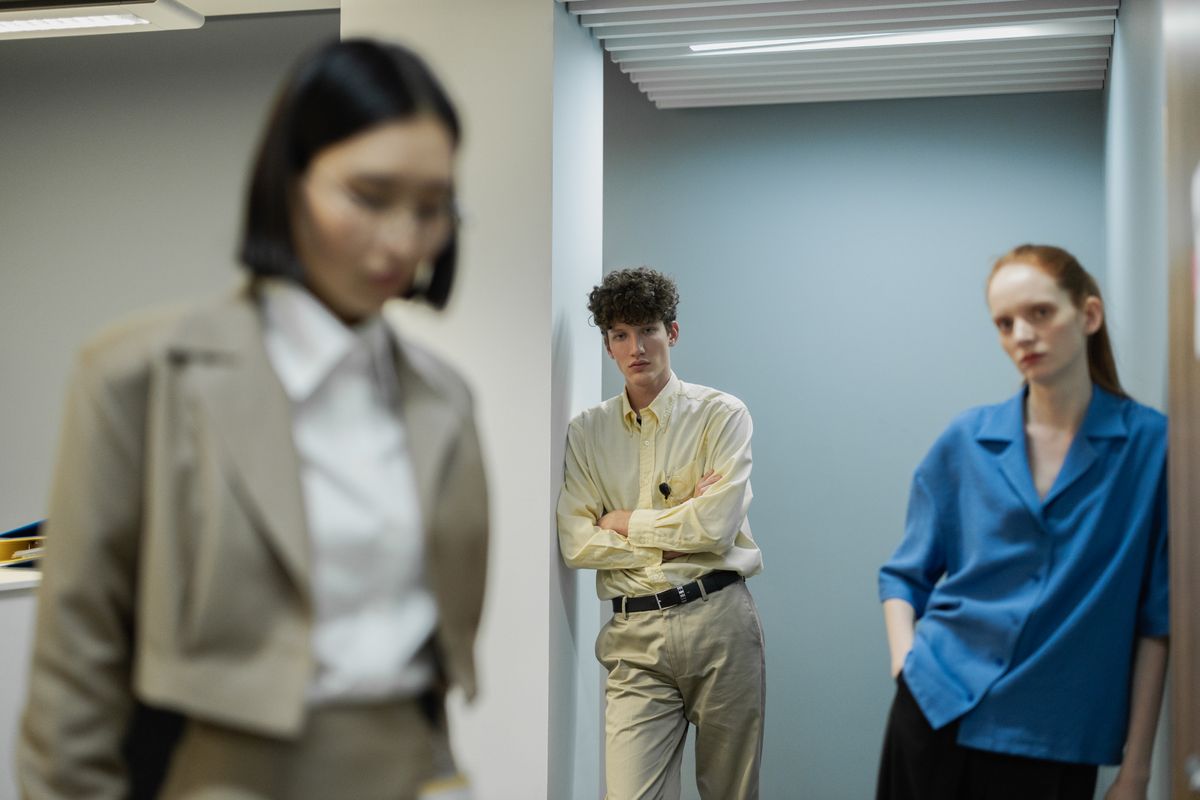 Three colleagues in an office hallway discussing work plans.