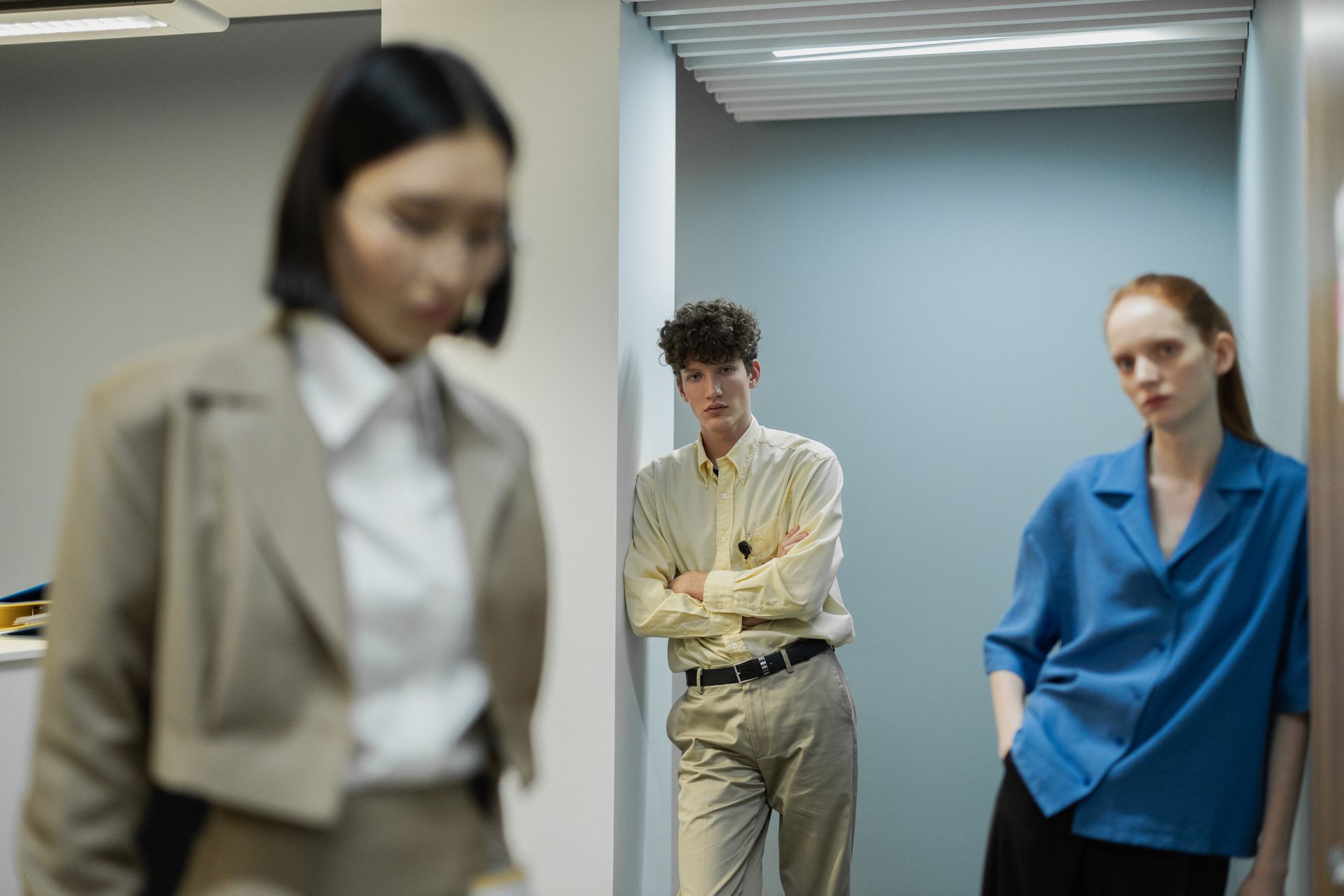 Three colleagues in an office hallway discussing work plans.