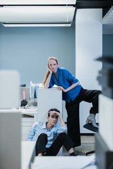 Two young professionals posing in a modern office environment, showcasing a contemporary work setting.