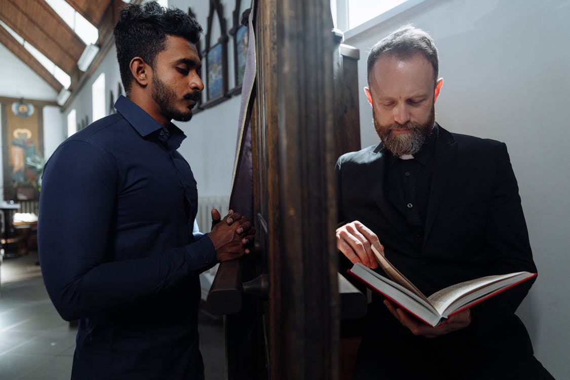 Free Priest Holding Bible While Listening to Man's Confession Stock Photo
