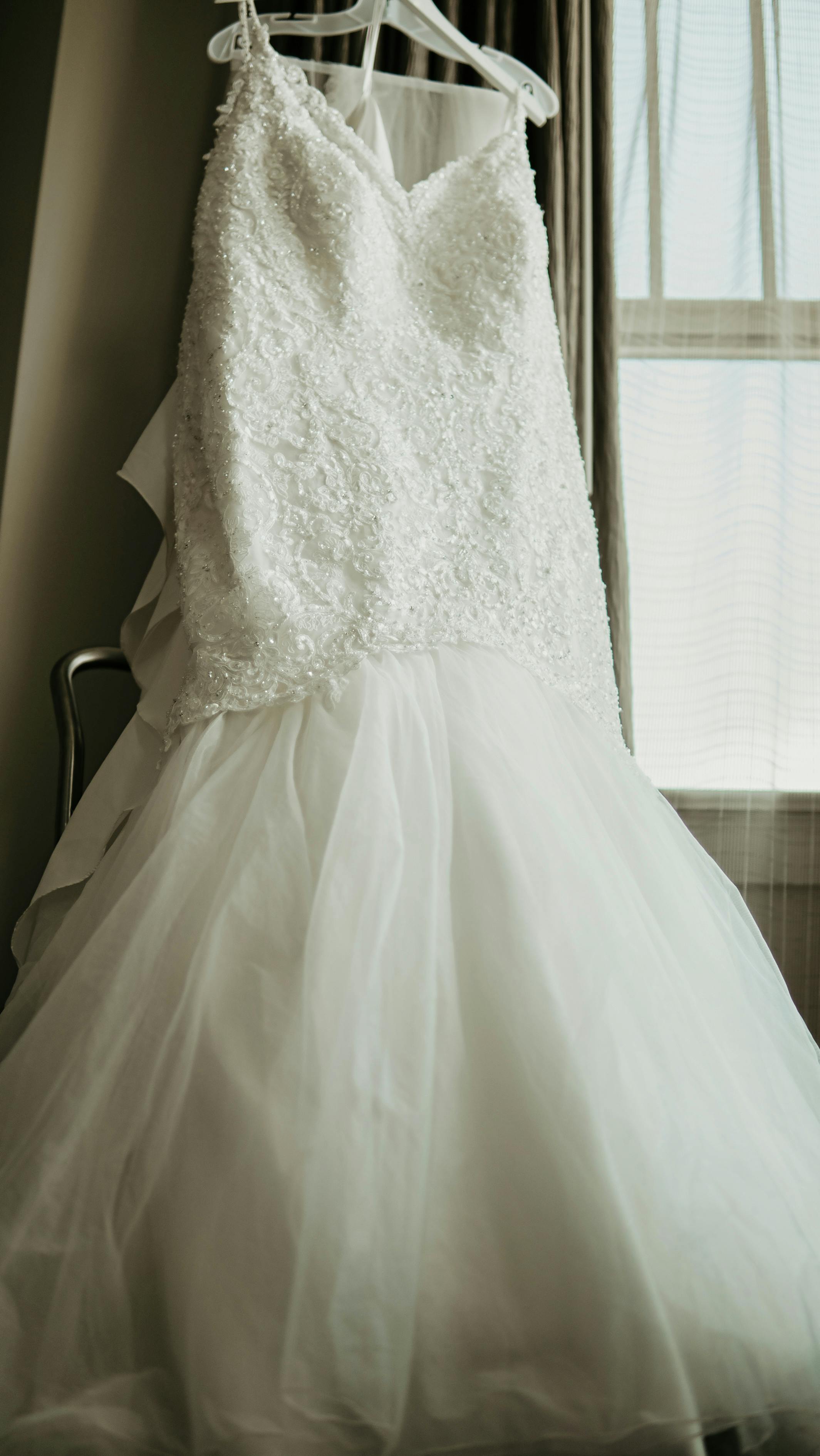 elegant wedding dress hanging in room