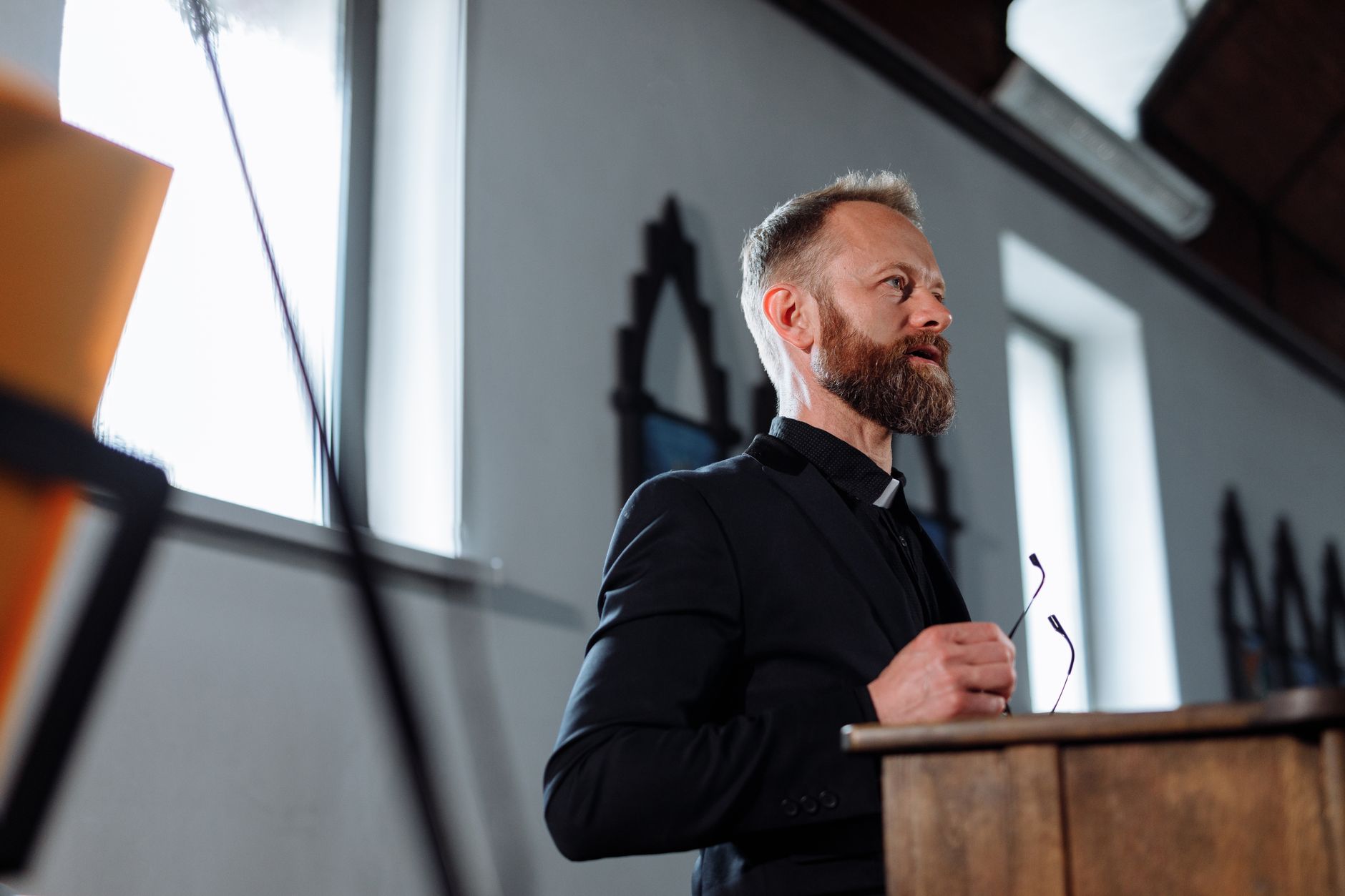 A priest passionately delivers a sermon from a pulpit inside a church.