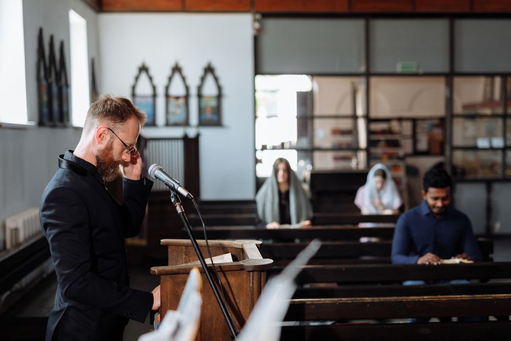 Pastor leading prayer with congregants seated in church