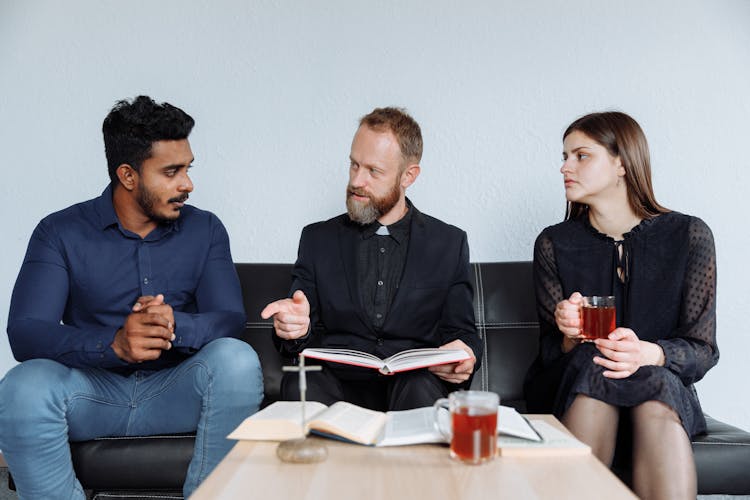 Three People Sitting On The Black Couch