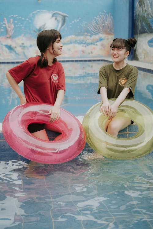 Free Women Smiling while Holding Inflatable Swim Rings Stock Photo