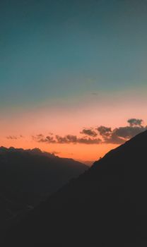 Capture the breathtaking view of a silhouetted mountain range at sunset, highlighting the dramatic sky and serene landscape.